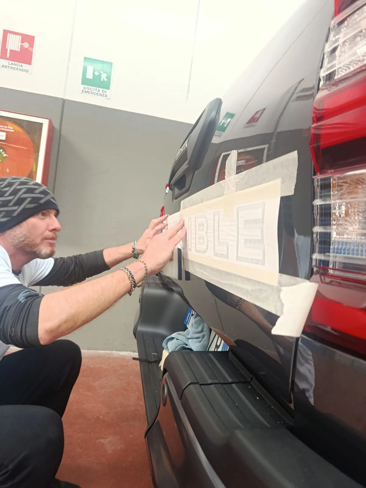 Applicazione a mano di una grafica adesiva sul paraurti di un'auto rossa
