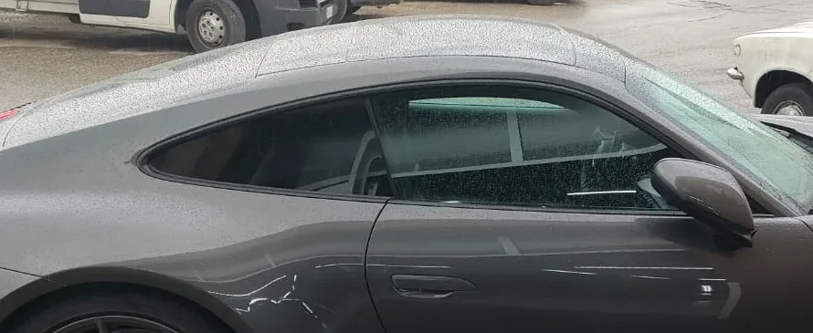 Porsche grigia di fianco con i vetri di serie: dal finestrino posteriore si vede dentro l'abitacolo